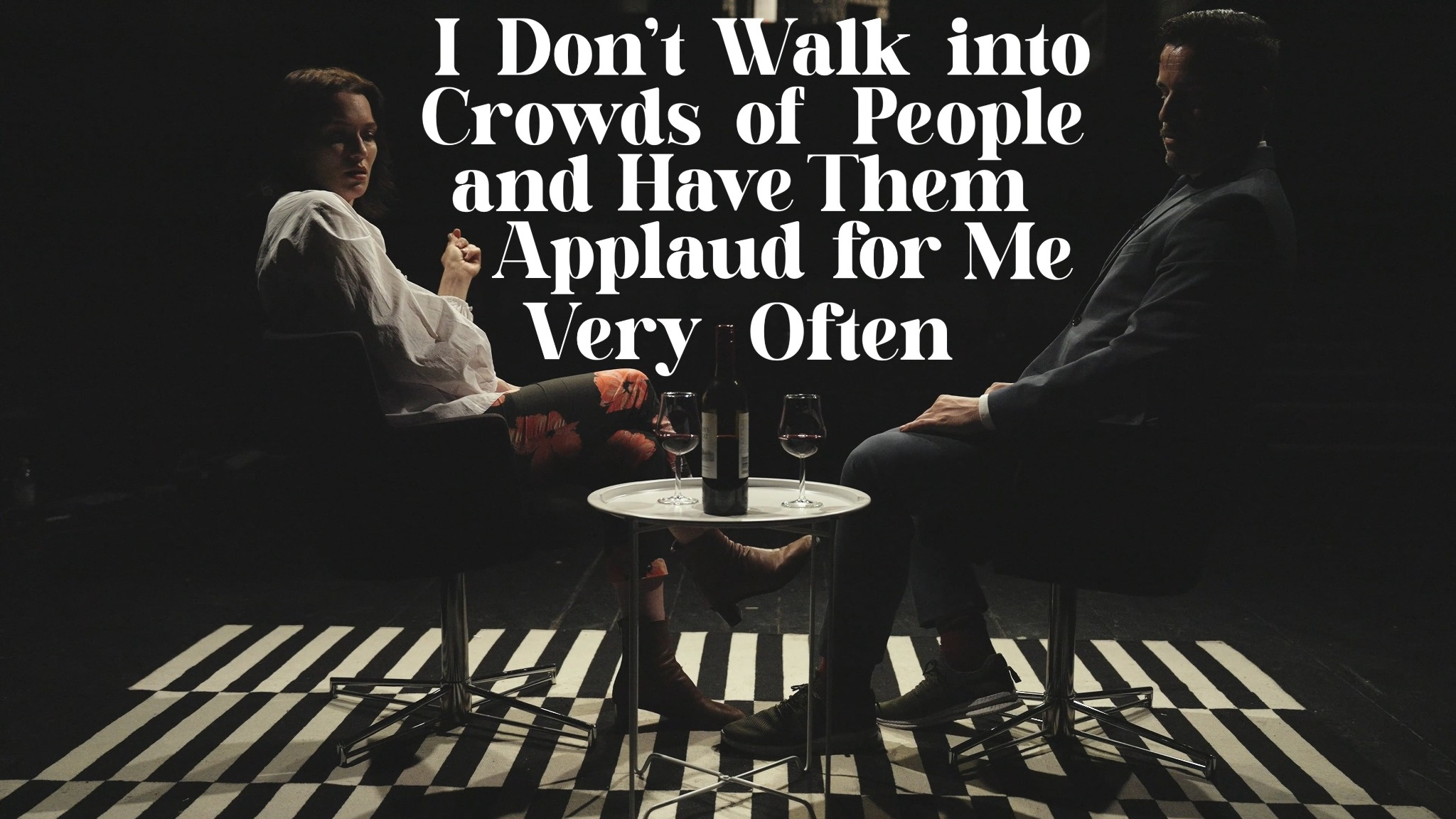 Two people facing each other on a dark stage in a still from I Don't Walk into Crowds of People and Have Them Applaud for Me Very Often